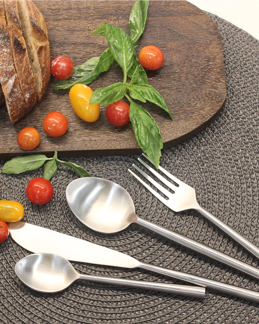 Stainless steel cutlery set with a butter knife spreading fresh tomato sauce on bread.